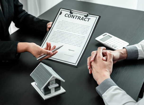 Agent nieruchomości prezentuje klientowi kredyt mieszkaniowy oraz omawia przy podpisywaniu decyzji formularz umowy, koncepcję Home Insurance i inwestycji nieruchomościowych. - Zdjęcie, obraz