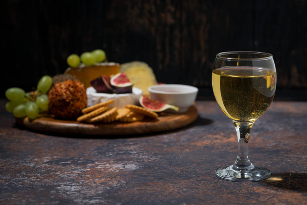 glass of white wine and snacks on dark background, horizontal - Valokuva, kuva