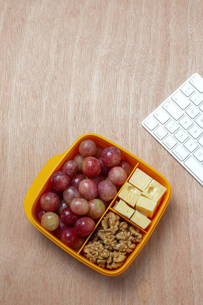 Healthy Food in Plastic containers ready to eat with Cheese, grapes and walnuts on the work table. To take away.walnuts - Photo, Image