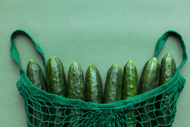 Vegetables in a string bag zero waste concept. cucumbers  juicy ripe eco bio fresh on background top view. No plastic shopping in the store. Farm Food Market. Vegan bag. total green one color  - Photo, image