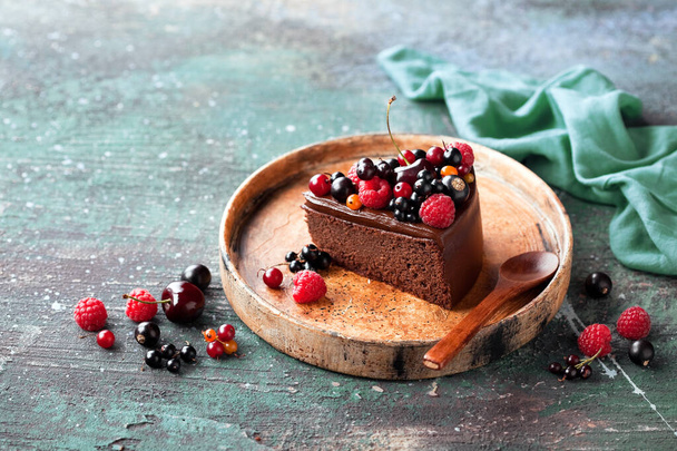 Stück Schokoladenkuchen mit Avocado-Zuckerguss und frischen Beeren, selektiver Fokus - Foto, Bild