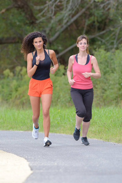 two women are jogging outdoors - Фото, изображение