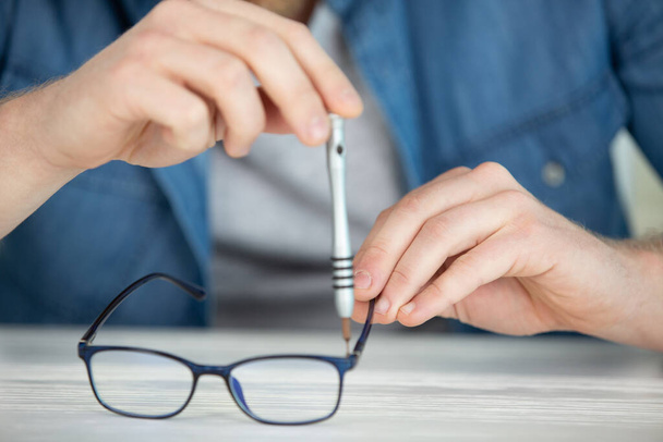 woman repairing glasses with screwdriver - Photo, Image
