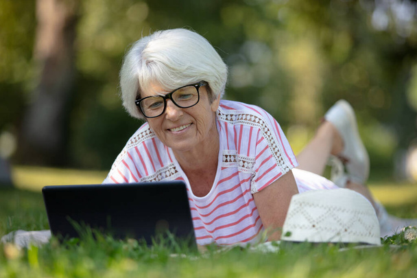 beautiful mature woman on laptop pc in park - Photo, Image