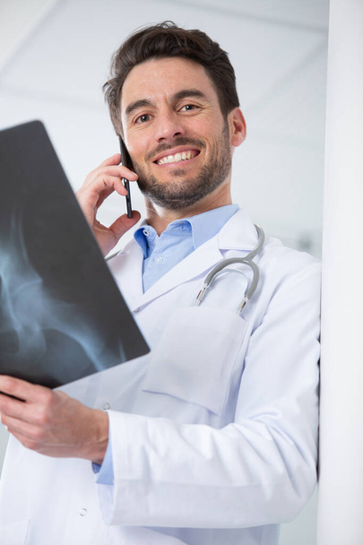 doctor telling good news on phone holding up x-ray image - 写真・画像