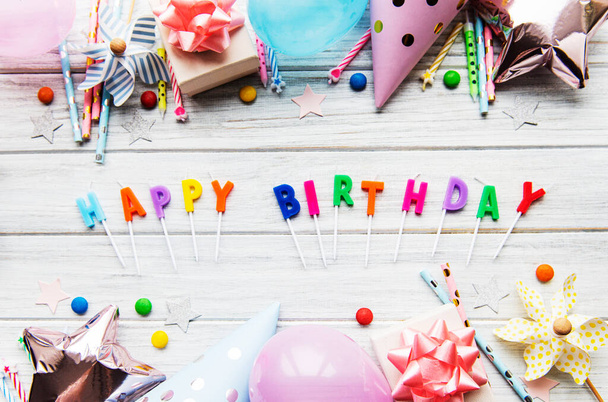Tekst Gelukkige verjaardag met kaarsbrieven met verjaardagsartikelen, kaarsen en confetti op witte houten ondergrond - Foto, afbeelding