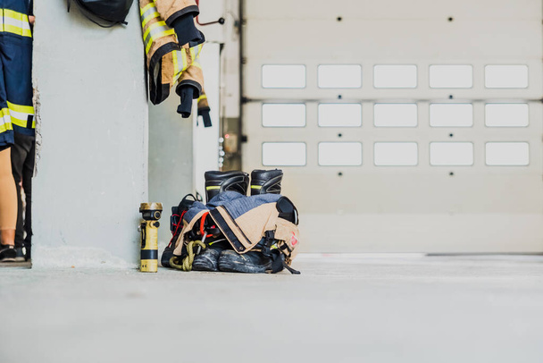 Dettaglio della tuta da lavoro di un vigile del fuoco preparato per l'azione accanto al materiale per spegnere gli incendi in sicurezza. - Foto, immagini