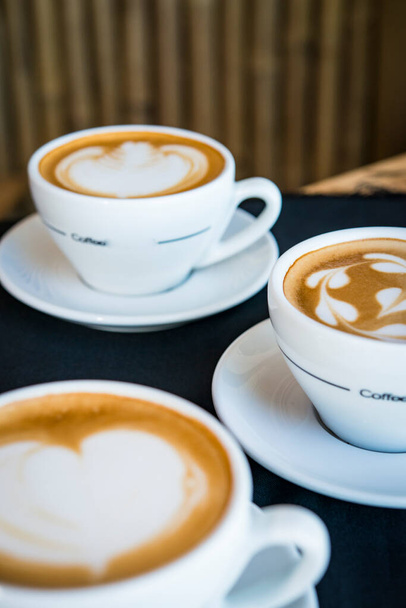 Drei Tassen heißen Cappuccino mit Herzkaffee auf Milch - Foto, Bild