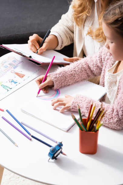 little girl drawing pictures with colorful pencils while visiting psychologist - Fotoğraf, Görsel