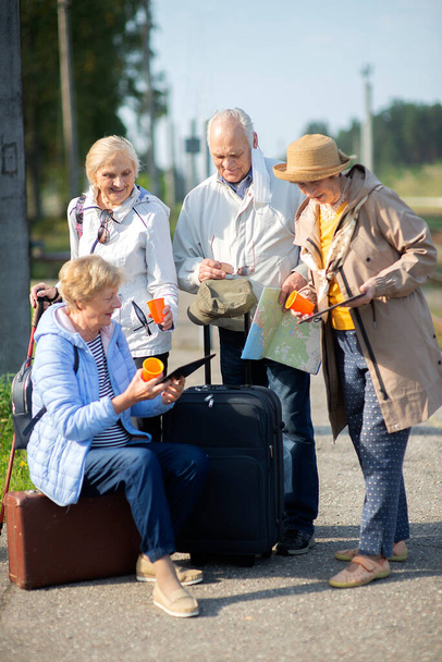 Gruppo di anziani positivi che guardano la mappa del viaggio durante la pandemia. COVID-19 viaggia nella Nuova Normale.  - Foto, immagini