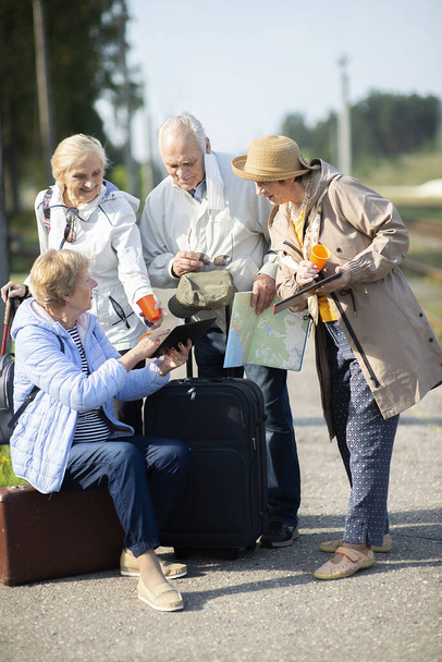 Grupo de personas mayores positivas mirando el mapa sobre el viaje durante la pandemia. COVID-19 viaja en la Nueva Normal - Foto, imagen