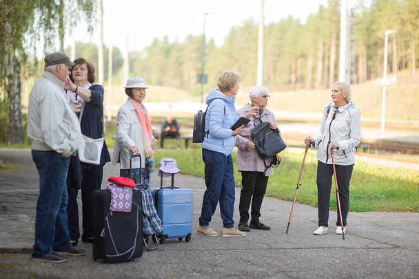 Um grupo de idosos idosos idosos positivos viajantes à espera de trem antes de ir em uma viagem - Foto, Imagem