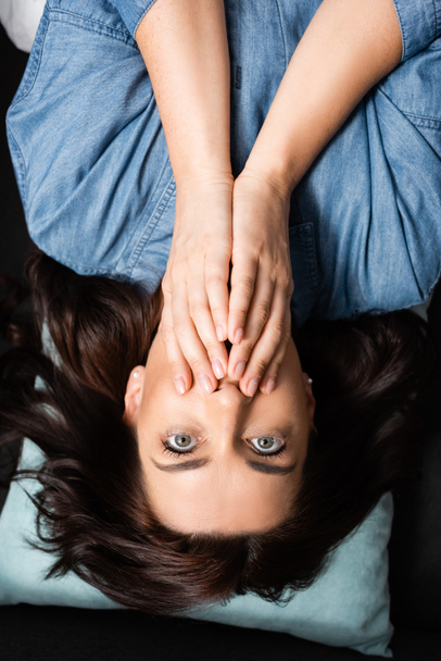 top view of terrified brunette woman covering mouth - Fotografie, Obrázek