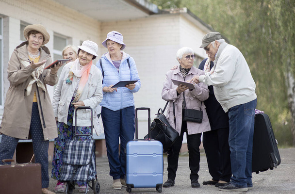 Grupo de personas mayores positivas mirando el mapa digital sobre el viaje durante la pandemia. COVID-19 viaja en la Nueva Normal.  - Foto, imagen