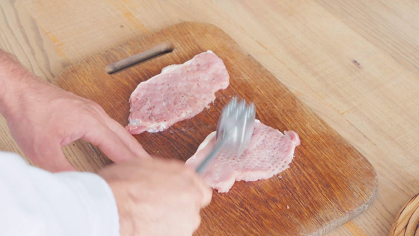 Vista recortada de rebanadas de cerdo aplanado chef con martillo en la tabla de cortar  - Metraje, vídeo