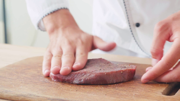 Vista ritagliata dello chef strofinando bistecca di manzo con spezie sul tagliere - Filmati, video