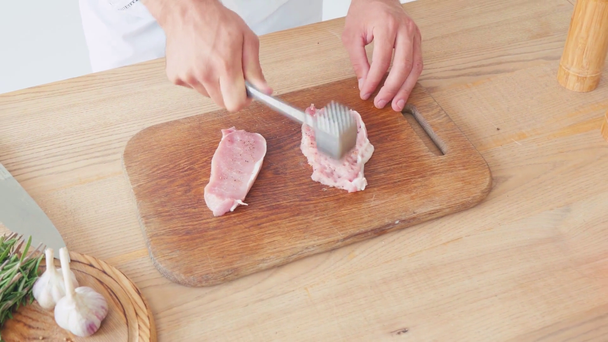 Vista ritagliata dello chef con taglierina di maiale appiattimento martello sul tavolo su bianco - Filmati, video