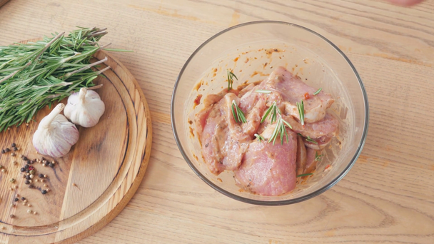 Vista ritagliata dello chef condimento marinato pollo a fette con rosmarino in ciotola - Filmati, video