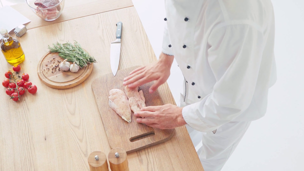 Vista ad alto angolo del condimento dello chef e strofinando il filetto di pollo sul tagliere - Filmati, video
