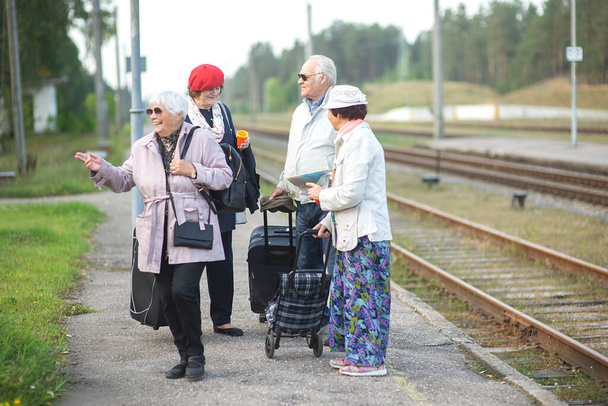 Grupo de personas mayores positivas que esperan tren antes de viajar durante una pandemia - Foto, Imagen