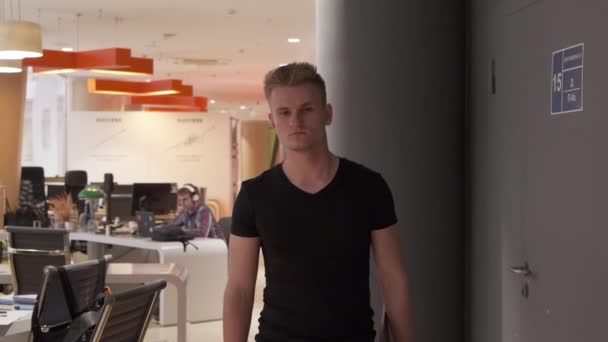 Um jovem homem europeu caminha por um escritório vazio no final da noite, executando um negócio startup - Filmagem, Vídeo