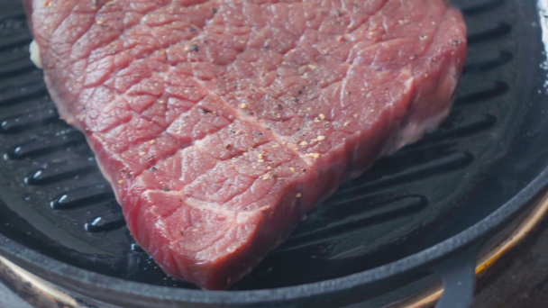 Vista da vicino bistecca di manzo speziata cruda sulla griglia - Filmati, video