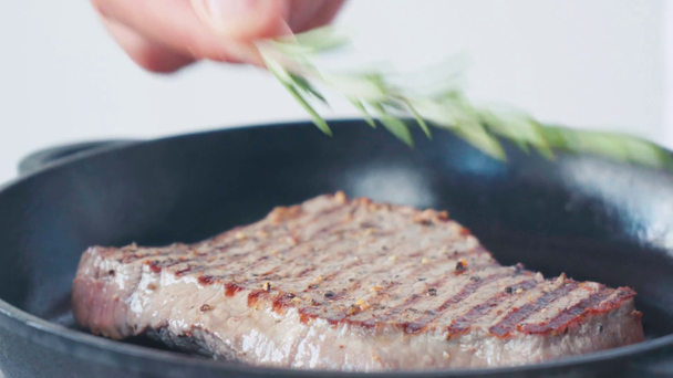 Close up view of chef greasing with rosemary juicy beef steak on grill pan - Záběry, video