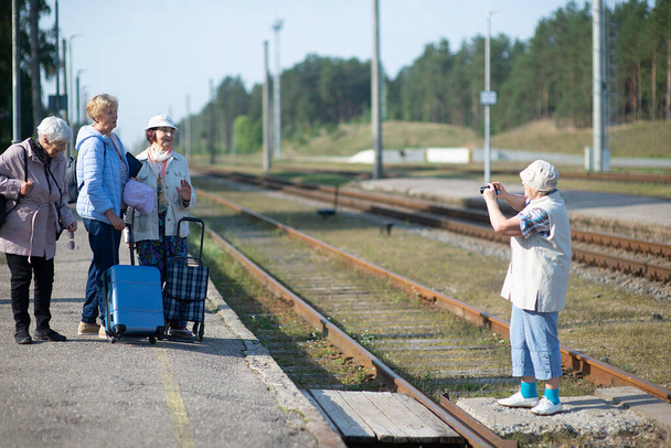 mujeres mayores toman una foto en una plataforma esperando que un tren viaje durante una pandemia de COVID-19 - Foto, imagen