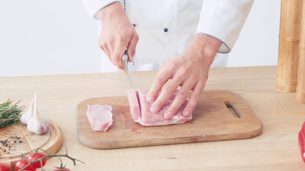 Вид на то, как повар режет свиную вырезку на доске на белом - Кадры, видео