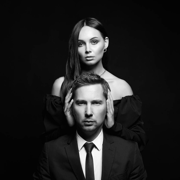portrait noir et blanc d'une belle femme avec un homme en costume. Couple sur fond noir. - Photo, image