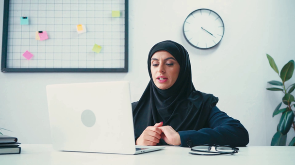 Mulher de negócios muçulmana tendo videochamada no laptop no escritório  - Filmagem, Vídeo