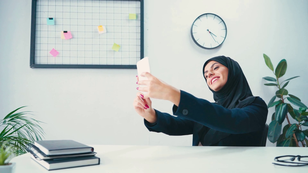 Muslim businesswoman taking selfie on smartphone in office  - Footage, Video