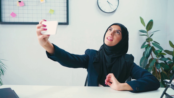Joven mujer de negocios musulmana tomando selfie en smartphone en la oficina  - Imágenes, Vídeo