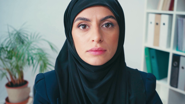 Молодая мусульманка-бизнесмен смотрит в камеру в офисе  - Кадры, видео