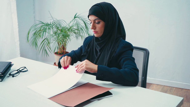 Muslimische Geschäftsfrau arbeitet im Amt mit Papieren  - Filmmaterial, Video