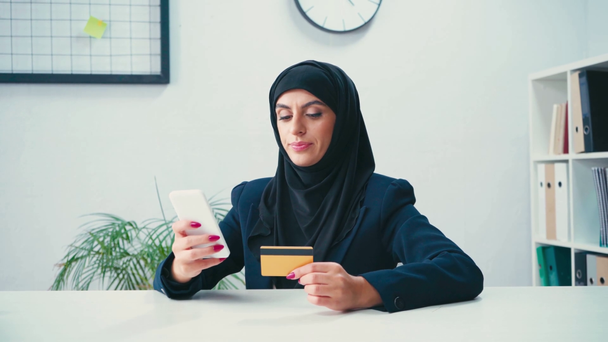 Empresaria musulmana usando smartphone y tarjeta de crédito  - Imágenes, Vídeo