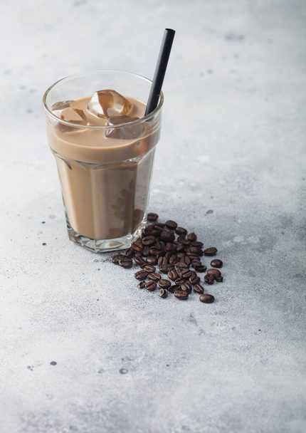 Glass of iced coffee with milk with fresh raw coffee beans on light  table background. - Photo, Image