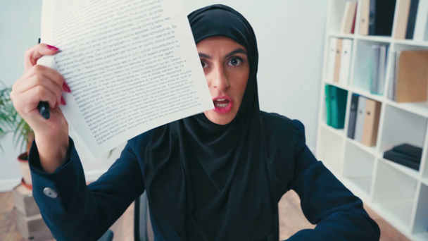 Enfadada mujer de negocios musulmana mostrando y arrugando papeles en la cámara  - Imágenes, Vídeo