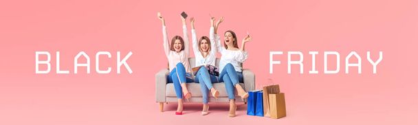Young women with shopping bags sitting on sofa against color background. Black Friday sale - Photo, Image