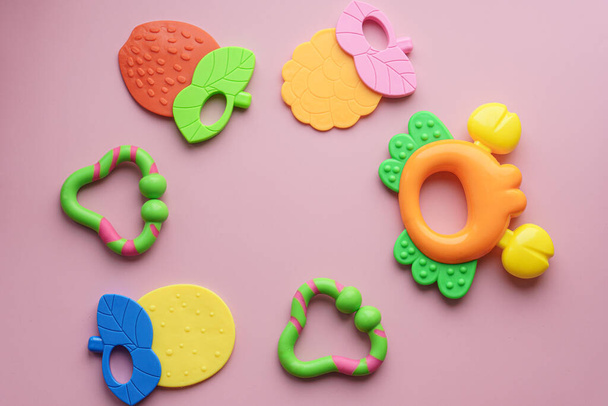 Dzieciństwo, miłość, opieka, higiena, niemowlęta - słowo zęby dziecka ułożone z kolorowych drewnianych liter na pastelowym różowym tle. duża kolorowa zabawka wykałaczka. ząbkowanie - Zdjęcie, obraz