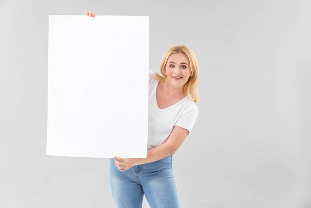 Woman with blank paper sheet on grey background - Φωτογραφία, εικόνα