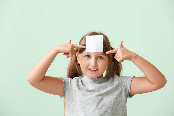 Menina com papel de nota em branco na testa contra fundo de cor - Foto, Imagem