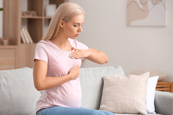 Young pregnant woman touching her breast at home - Zdjęcie, obraz