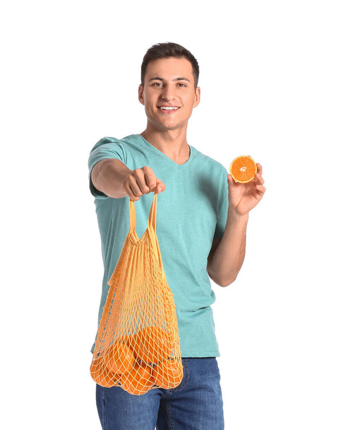 Handsome man with ripe oranges on white background - Photo, Image