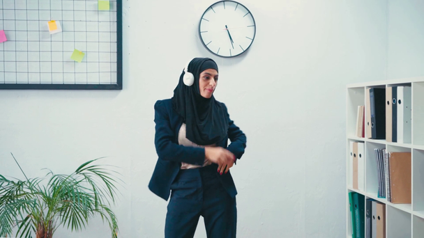 Muslimská podnikatelka ve sluchátkách tančí v kanceláři  - Záběry, video
