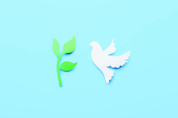 色の背景に紙鳩とオリーブの枝。国際平和の日 - 写真・画像