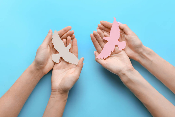 Женские руки с бумажными голубями на цветном фоне. Международный день мира - Фото, изображение