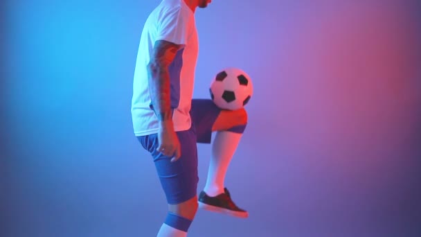 Férfi focista zsonglőrködik labdát lábon a stúdióban - Felvétel, videó