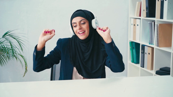 Muslimská podnikatelka ve sluchátkách zpívá a tančí v kanceláři  - Záběry, video