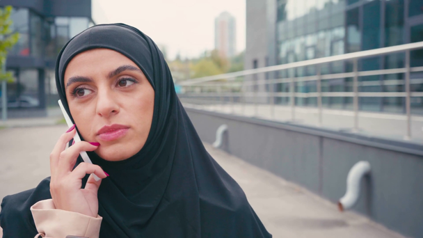 Moslim vrouw in hijab praten op smartphone buiten - Video